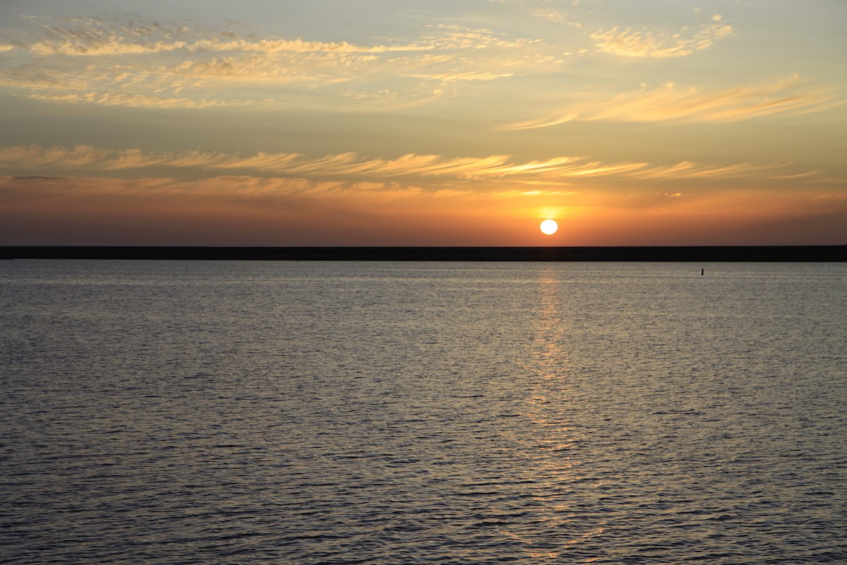 De zon zakt langzaam richting de dijk